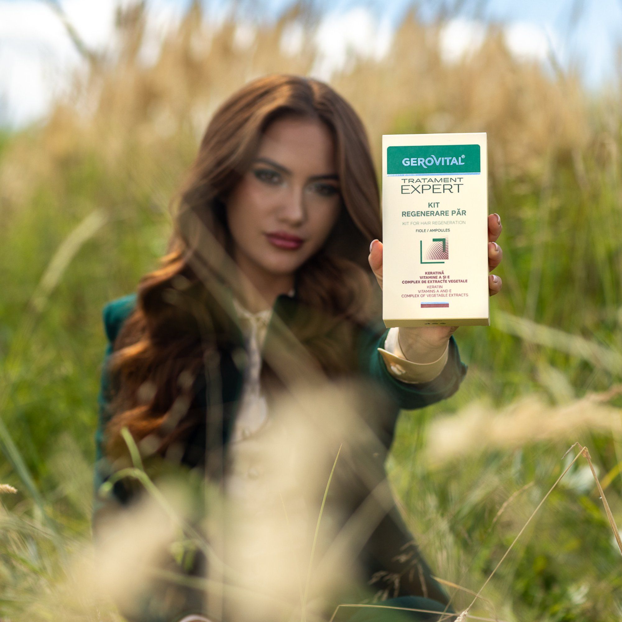 Frau hält Gerovital Expert Kit in der Hand. Hintergrund: Feld mit hohem Gras. Verpackung mit grünen Akzenten.