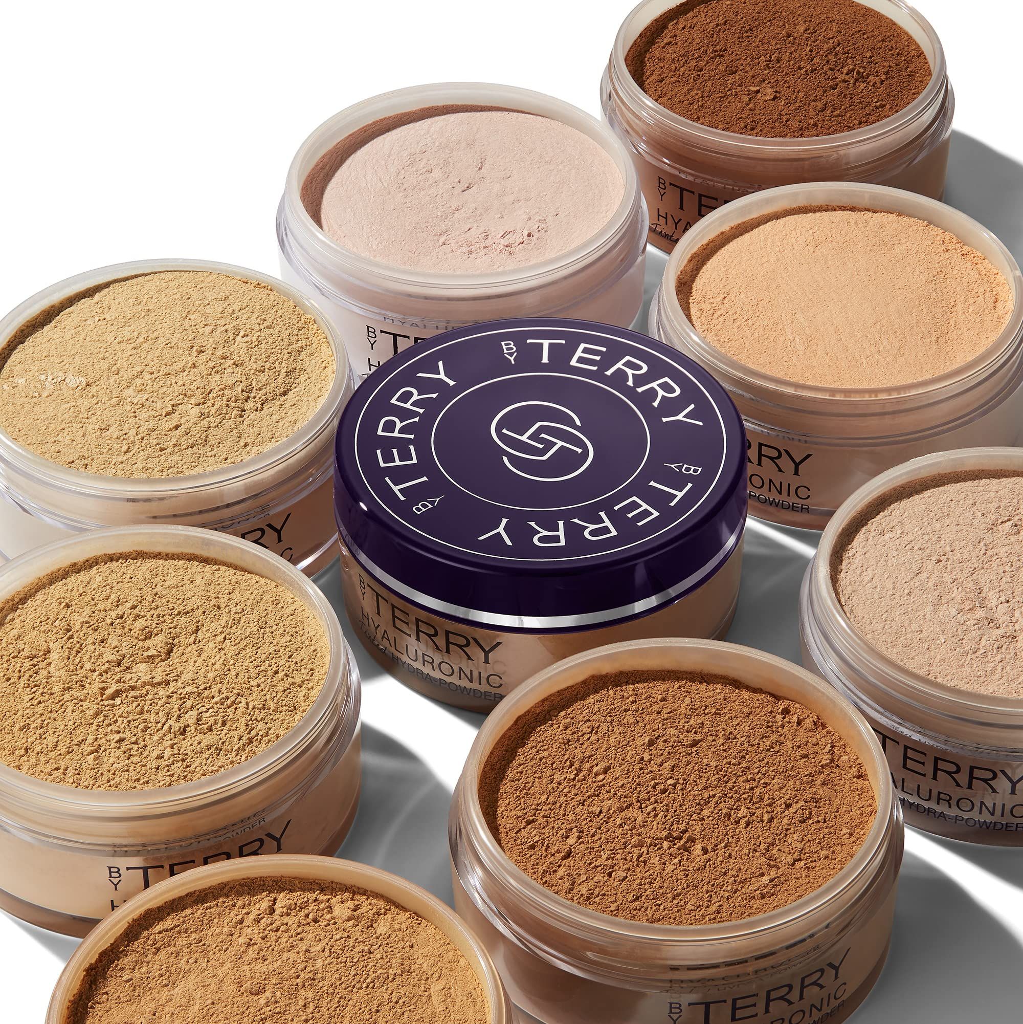 Mehrere Behälter mit Puder. Deckel mit Logo und Schriftzug "BY TERRY HYALURONIC".