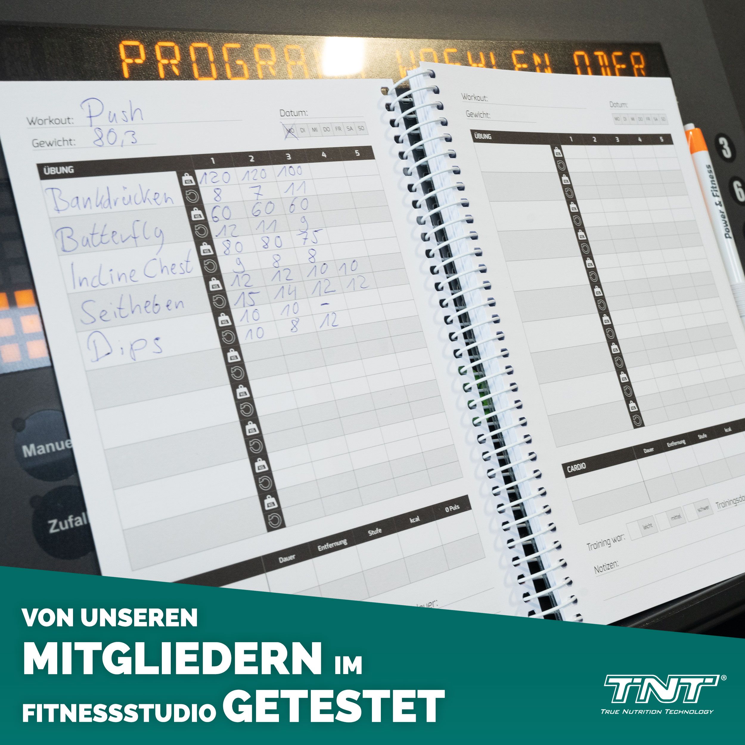 Offenes Trainingsbuch mit Spiralbindung. Tabellen und Notizen. Text: VON UNSEREN MITGLIEDERN IM FITNESSSTUDIO GETESTET. Logo: TNT.