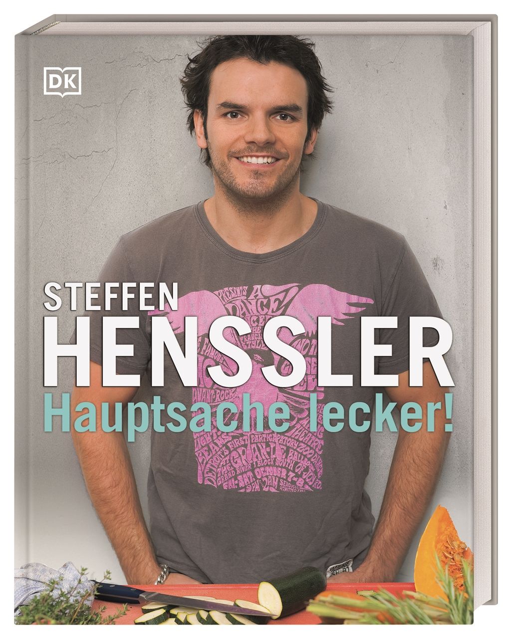 Buchcover mit Steffen Henssler. Titel: Hauptsache lecker! Logo DK. Auf einem Tisch liegen Gemüse. Der Autor lächelt.