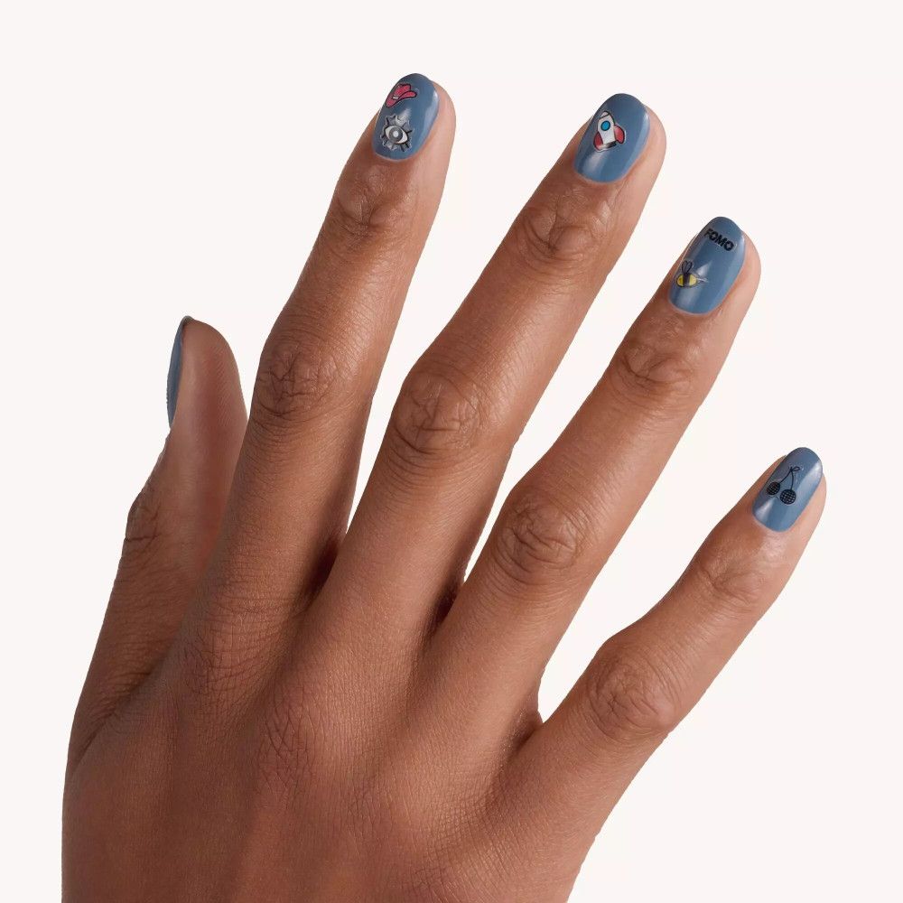 Hand mit blau lackierten Nägeln. Auf den Nägeln sind Nagelsticker mit verschiedenen Motiven angebracht.