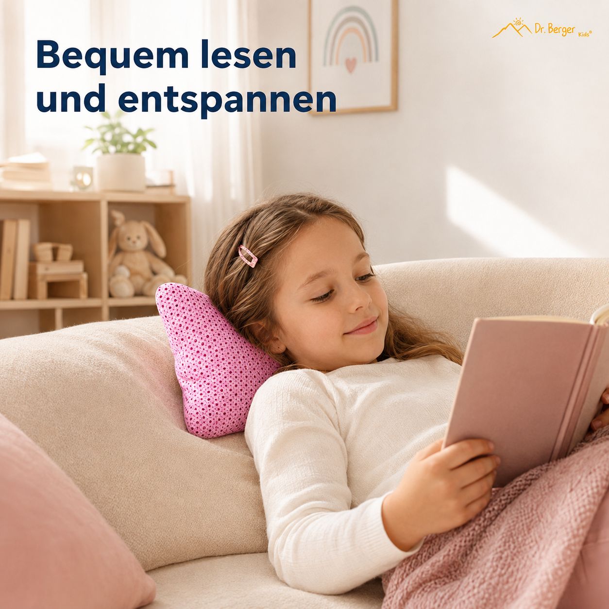 Mädchen liest auf Sofa mit rosa Lese-Kissen im Nacken.
