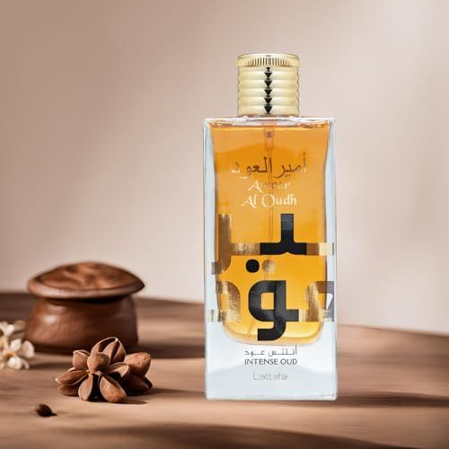 Rechteckige Glasflasche mit goldfarbenem Verschluss. Aufschrift: Ameer Al Oudh Intense Oud. Auf Holzoberfläche.