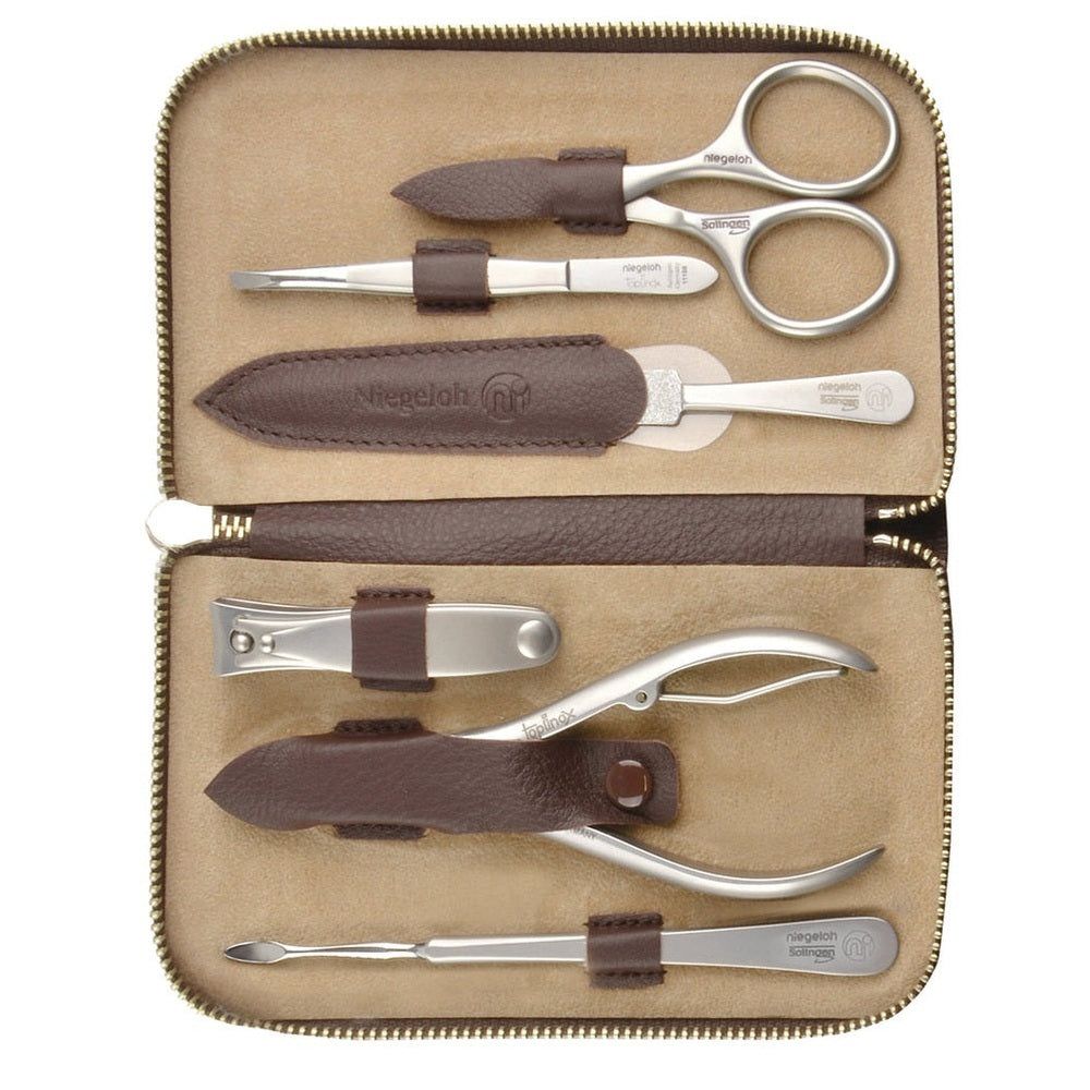 Etui mit Maniküre-Set. Enthält Schere, Pinzette, Nagelfeile, Nagelknipser, Nagelzange und Hautschieber. Braunes Lederetui.