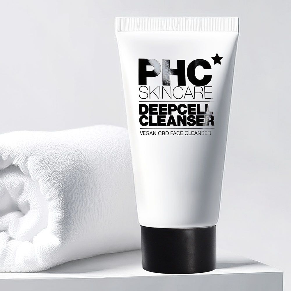 Weiße Tube mit schwarzem Deckel. Aufschrift: PHC Skincare Deepcell Cleanser. Vegan CBD Face Cleanser. Neben einem weißen Handtuch.