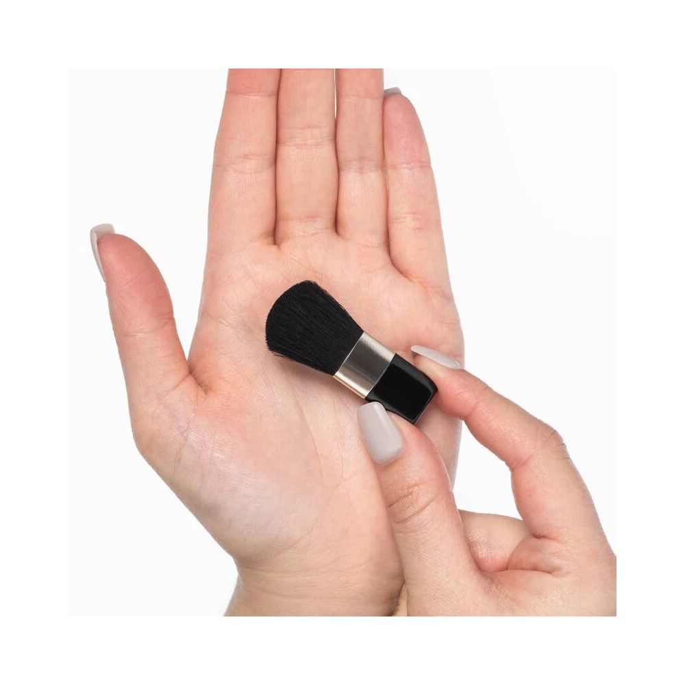 Pinsel Blush, schwarz, mit silberfarbener Manschette. Gehalten in einer Hand, die andere Hand hält den Pinsel.