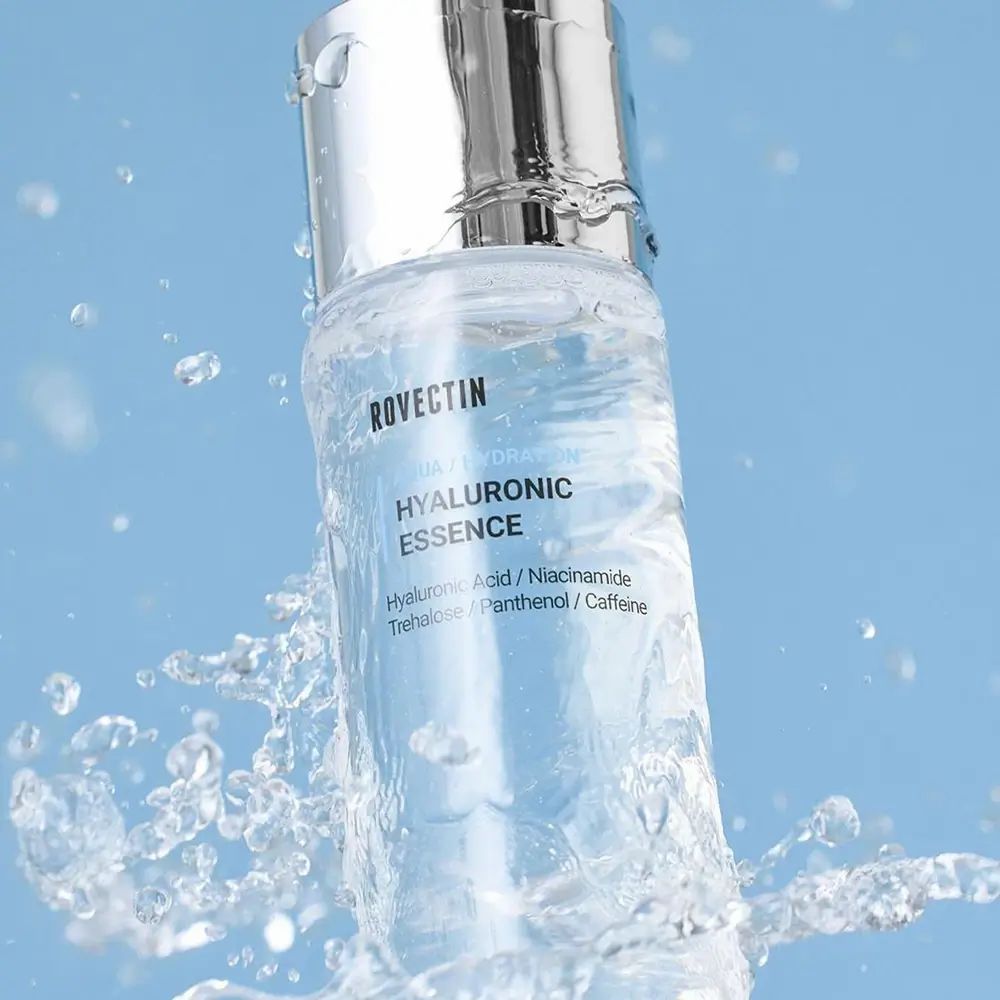 Produktflasche mit silbernem Deckel, umgeben von Wasserspritzern. Aufschrift: ROVECTIN, AQUA / HYDRATION, HYALURONIC ESSENCE. Produkt im Wasser.