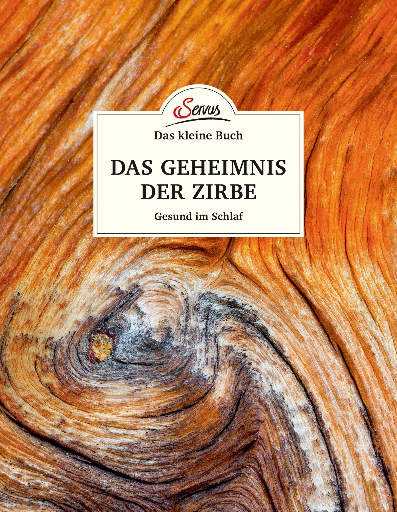 Buchcover mit Holzmaserung. Titel: Das kleine Buch: Das Geheimnis der Zirbe. Untertitel: Gesund im Schlaf. Logo: Servus.