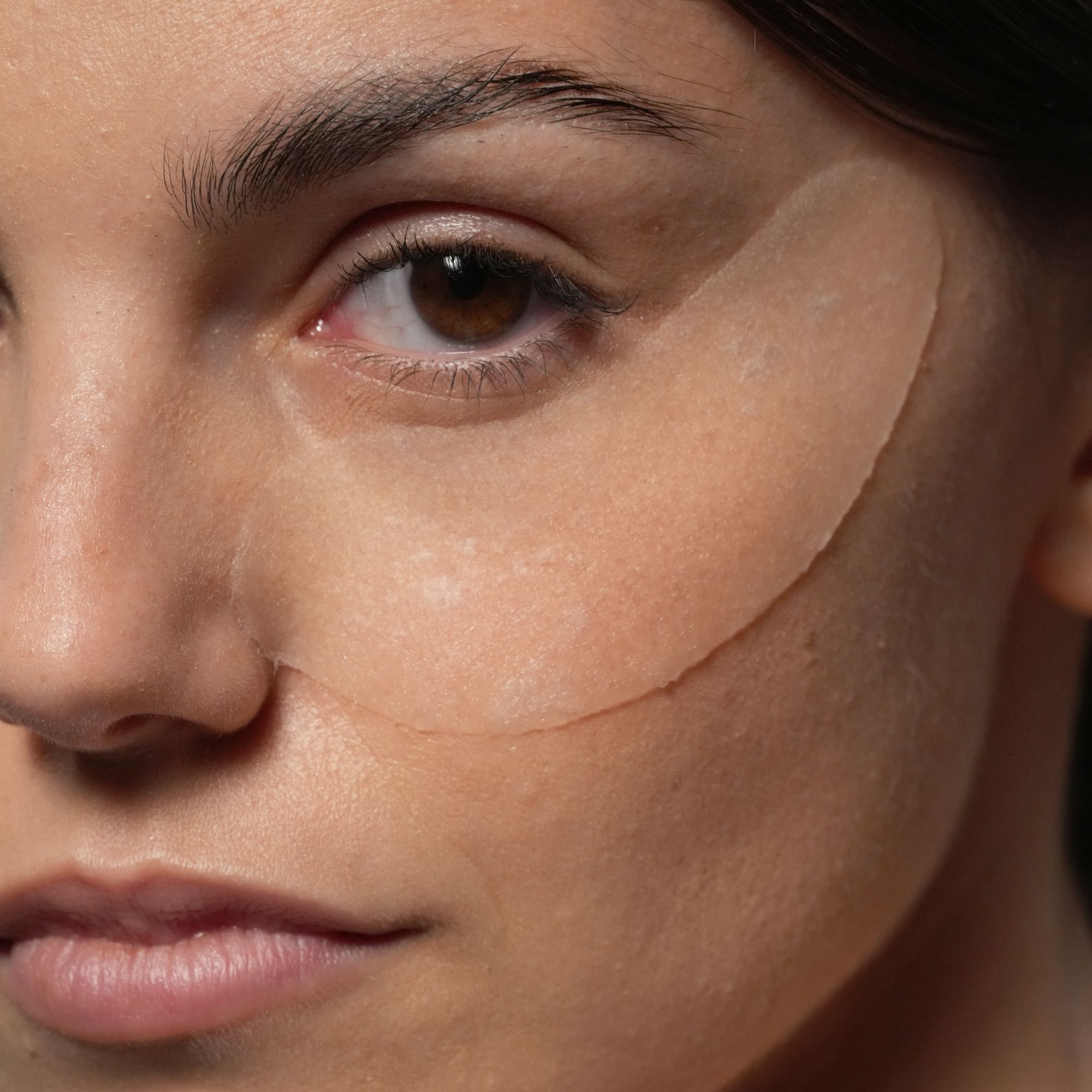 Nahaufnahme einer Frau mit durchsichtigen Augenpads unter den Augen.