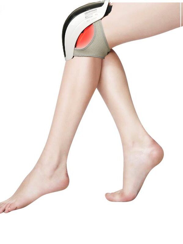 Knie-Massagegerät am Bein. Gerät am Knie, rotes Licht sichtbar. Bein im Bild.