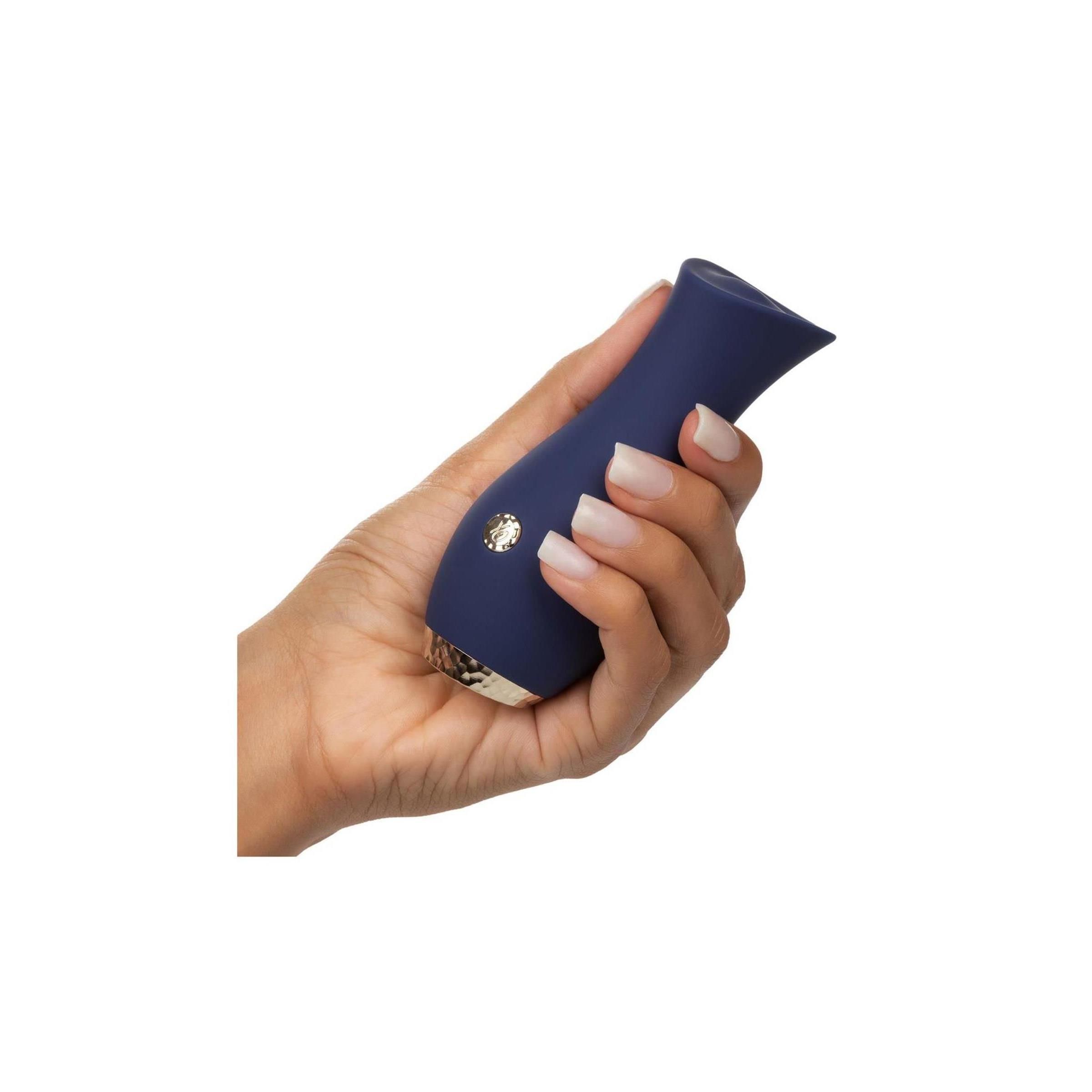 Hand hält blaues, tulpenförmiges Produkt mit silberfarbenem Boden und Knopf.