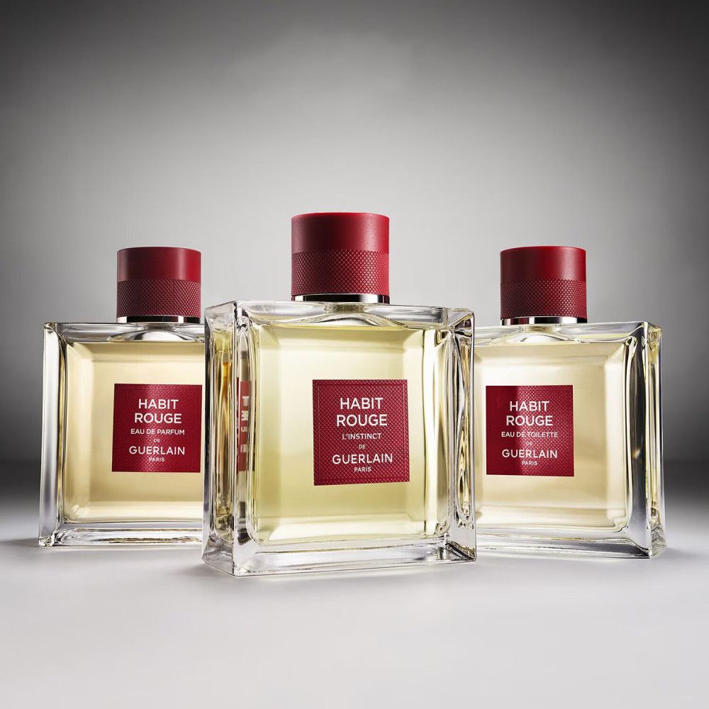 Drei quadratische Glasflakons mit roten Verschlüssen. Rote Etiketten mit weißer Schrift: Habit Rouge, Eau de Toilette, Guerlain Paris.