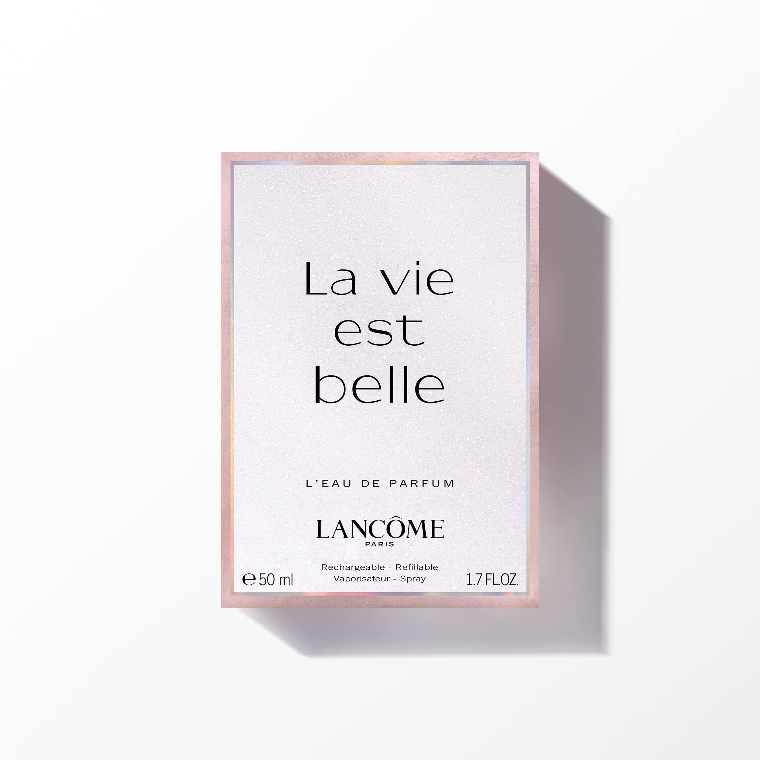 Verpackung mit Text: La vie est belle, L'EAU DE PARFUM. Rosa Hintergrund, weißer Text, silberner Rahmen.