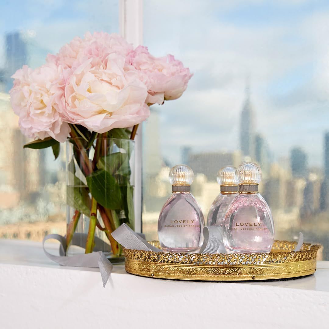 Parfümflaschen auf Tablett vor Fenster. Goldfarbenes Tablett. Blick auf Stadt.