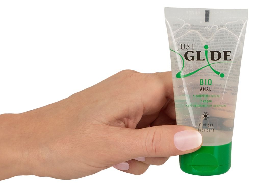 Hand hält Tube mit grünem Verschluss. Aufschrift: Just Glide Bio Anal. Produkt in transparenter Verpackung.