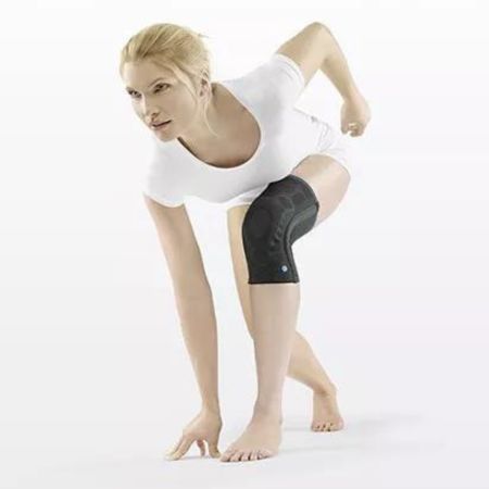 Person in Sportkleidung mit Kniebandage. Schwarze Bandage am linken Knie. Frau in Bewegung, Blick nach links.