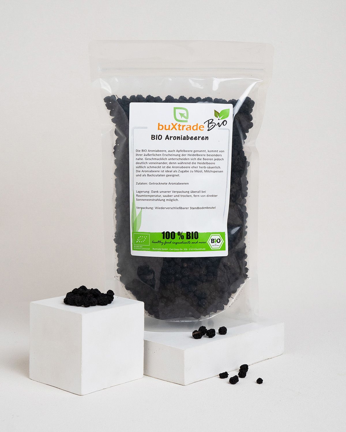 Verpackung mit buXtrade Bio Aroniabeeren auf Podest. Aufdruck: 100% BIO. Grün-weißes Logo.