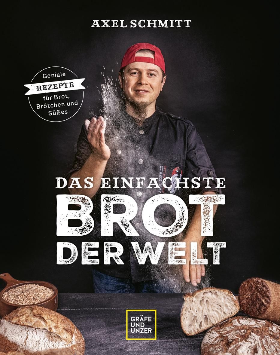 Buchcover: "Das einfachste Brot der Welt". Autor Axel Schmitt. Mann wirft Mehl. Brot und Zutaten auf Tisch.