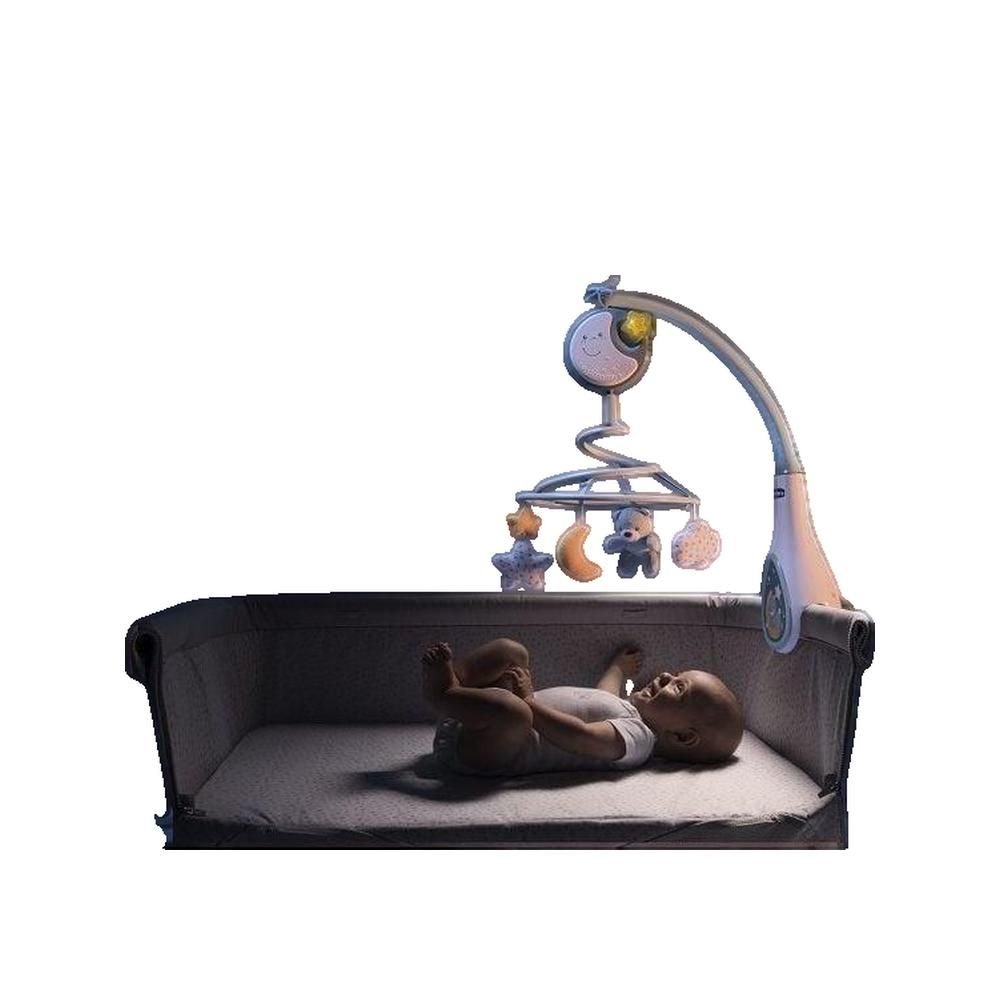 Baby liegt in einem Bett. Ein Mobile mit Mond, Sternen und Bären ist darüber angebracht. Das Mobile ist an einem Bogen befestigt.