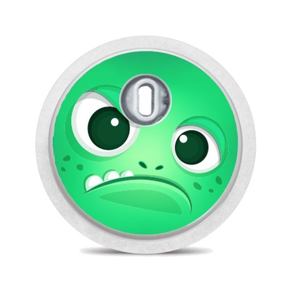 Runder Aufkleber mit grünem Monstergesicht. Ein Auge, Zähne. Mit silbernem Applikator.
