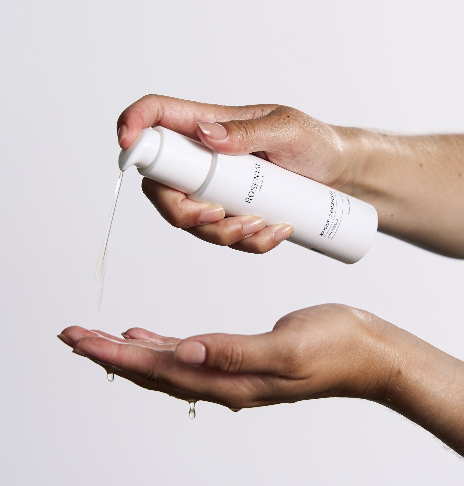 Weiße Flasche mit Pumpe, Öl wird in die Hand gegossen. Produktname: Rosental Organics.