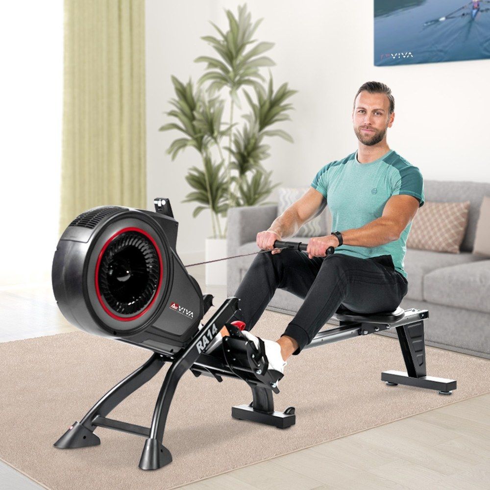 Mann trainiert auf dem AsVIVA Rudergerät Magnetic Rower RA14 in einem Wohnzimmer.