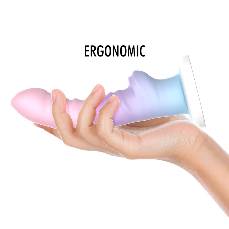 Ergonomisch geformter Dildo in Rosa, Lila und Blau, gehalten in einer Hand. Weißer Sockel.