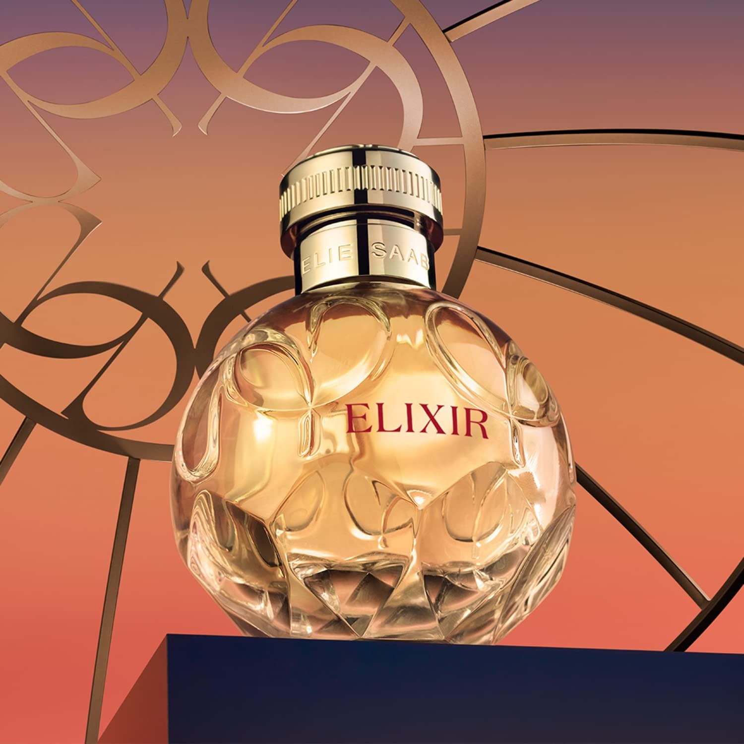 Runder Flakon mit goldfarbenem Verschluss. Aufschrift "ELIXIR" und "ELIE SAAB". Hintergrund mit goldenen Elementen.