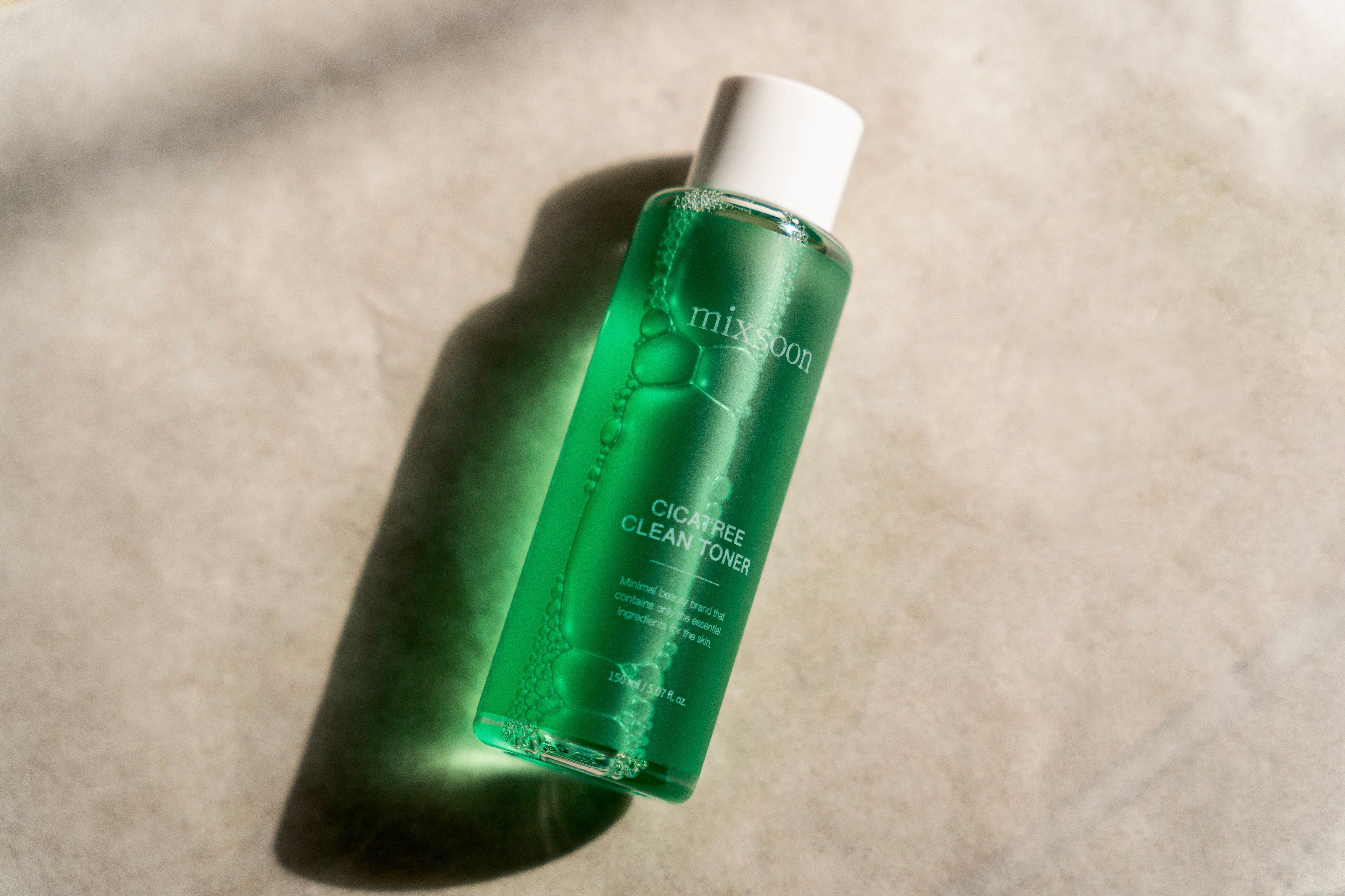 Grüne Flasche mit weißem Deckel. Aufschrift: mixsoon, Cicatree Clean Toner. Schatten. Hintergrund: hell.