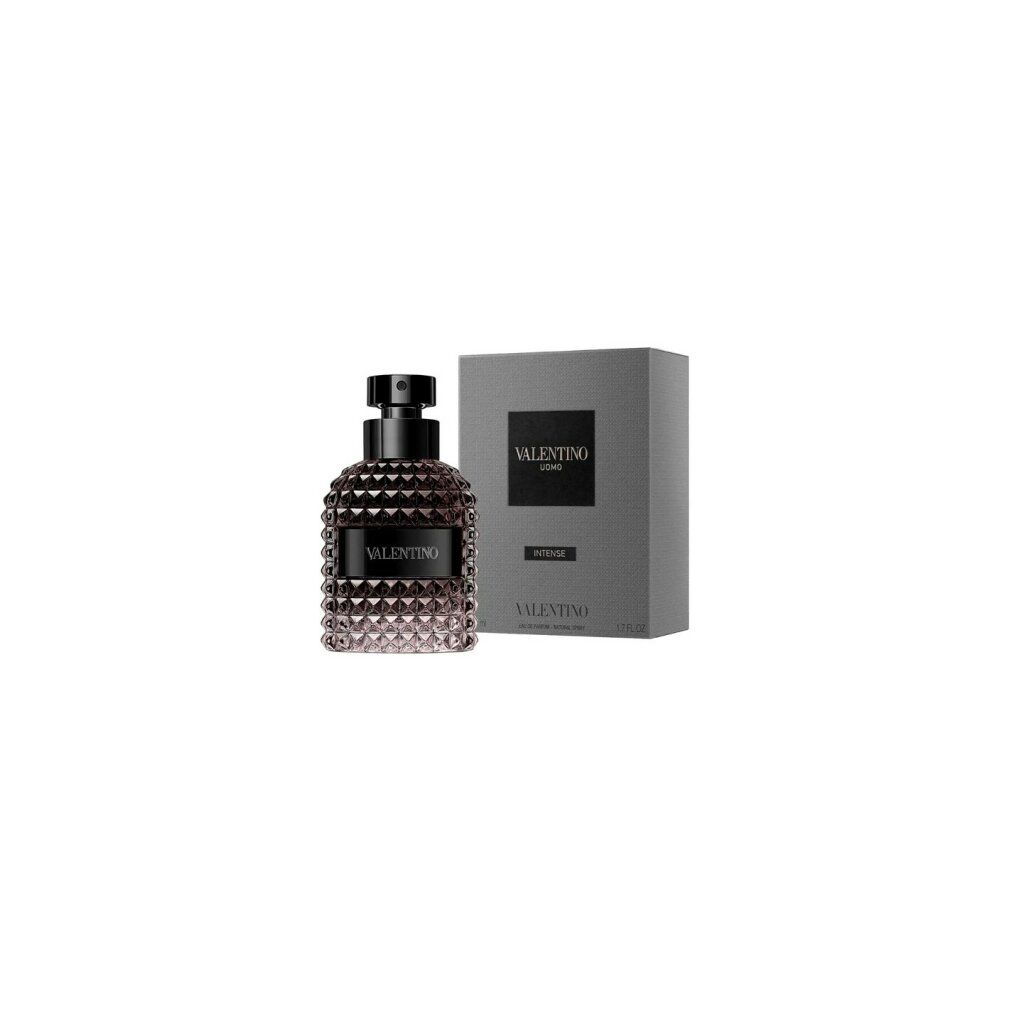 Parfümflakon und graue Verpackung. Flakon mit schwarzem Verschluss und geprägtem Muster. Verpackung mit Logo und Produktbezeichnung.