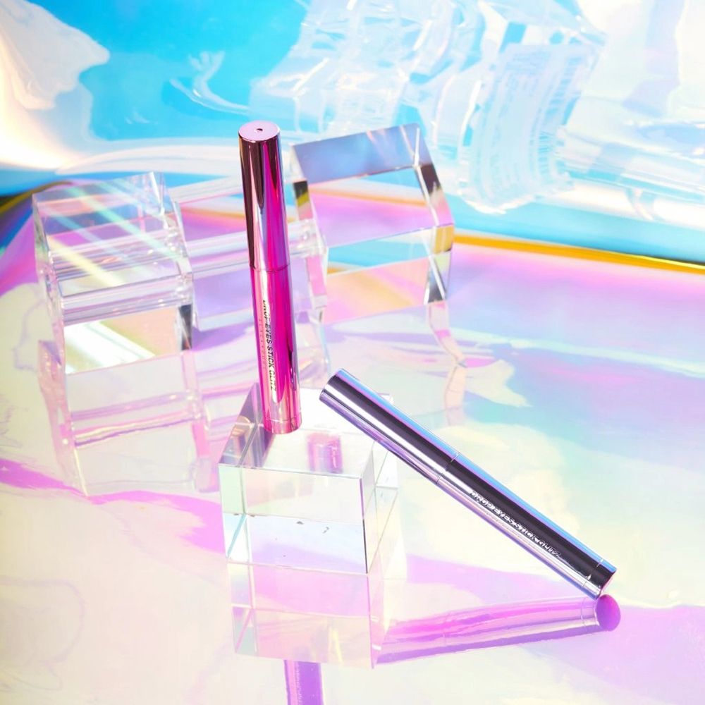 Rosa Drop Eyes Stick Glitz Lidschatten auf Glasblöcken. Hintergrund mit Farbverlauf. Aufschrift: Drop Eyes Stick Glitz.