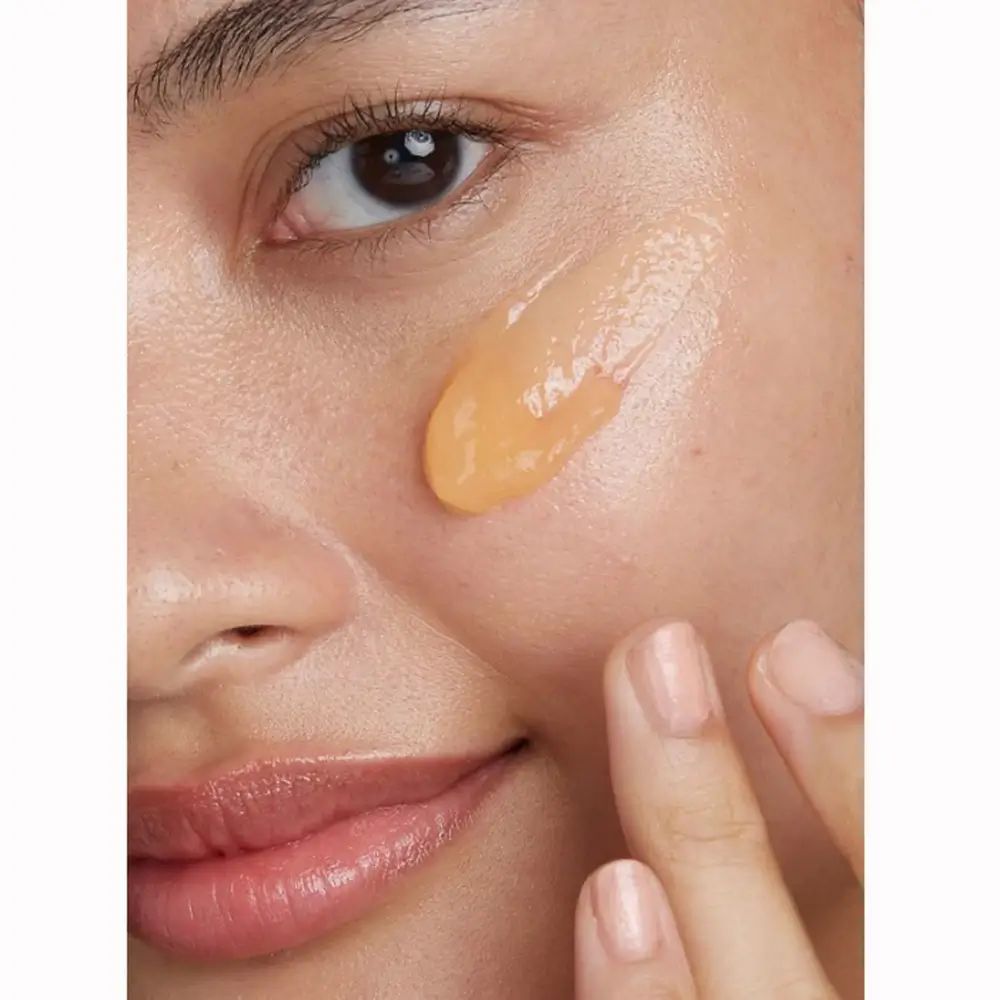 Nahaufnahme eines Gesichts mit orangefarbenem Gel auf der Haut. Zeigt Haut und Lippen.