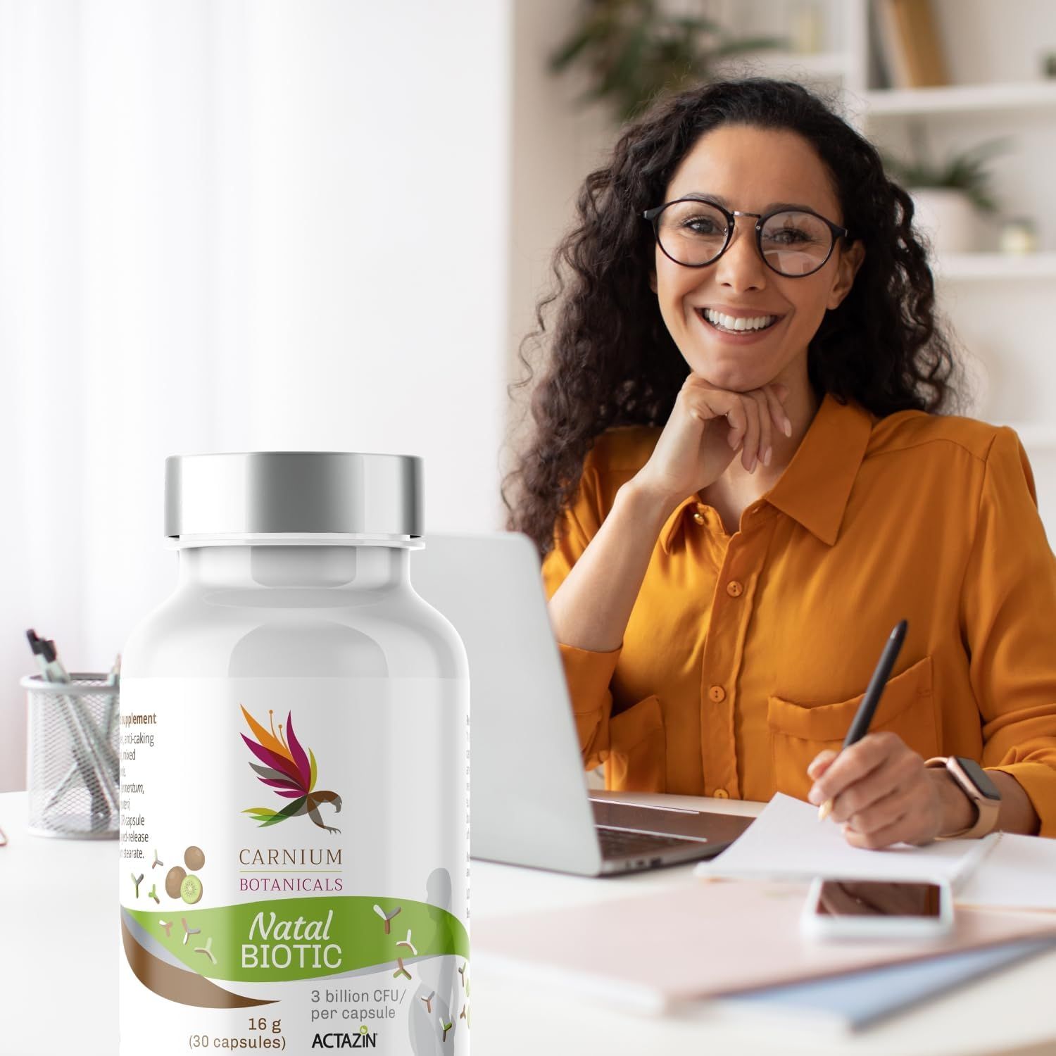 Weiße Flasche mit silbernem Deckel. Aufschrift: Carnium Botanicals Natal Biotic. Frau am Schreibtisch.