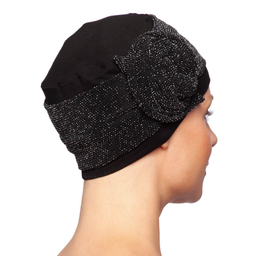 Schwarzer Turban mit glitzernder Blüte. Seitenansicht auf einer Frau.