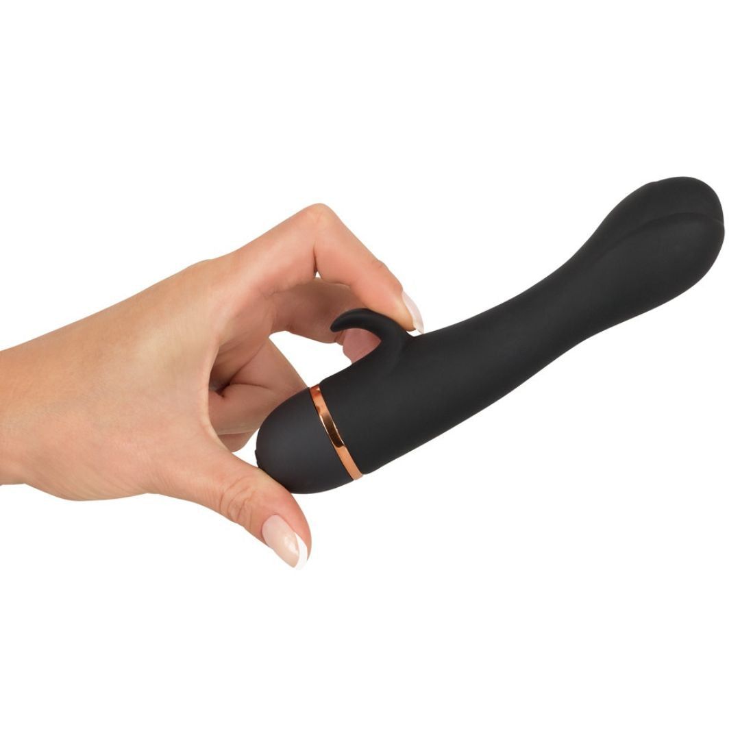 Schwarzer Vibrator, gehalten von einer Hand. Tulpenförmiger Kopf, Blatt-Klitorisreizer und goldfarbener Ring.