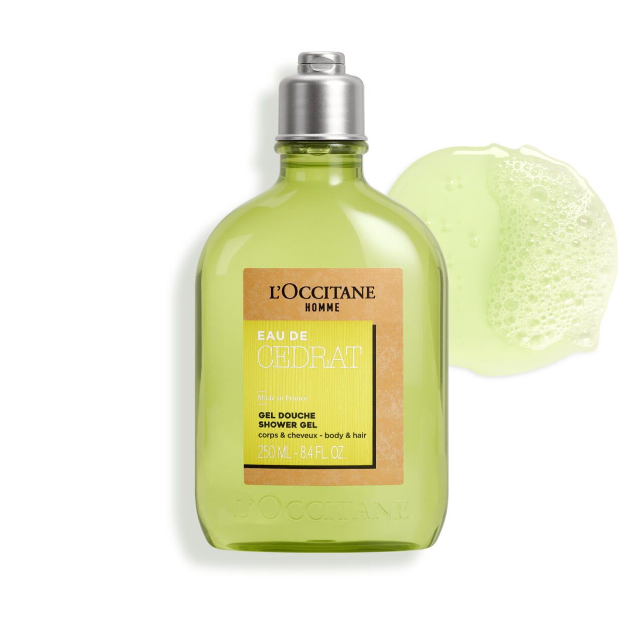 Grünes Duschgel in Flasche mit silbernem Deckel und Klecks Duschgel daneben. Aufkleber mit Text: Eau de Cédrat, Gel Douche, L'Occitane.