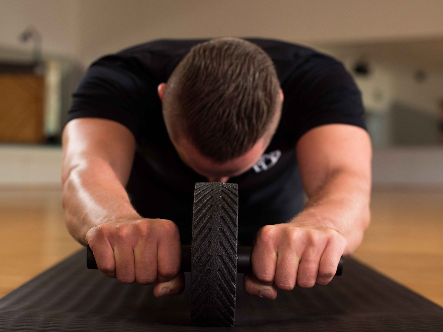 Person nutzt einen Ab Roller auf einer Matte. Der Fokus liegt auf dem Rad und den Händen.