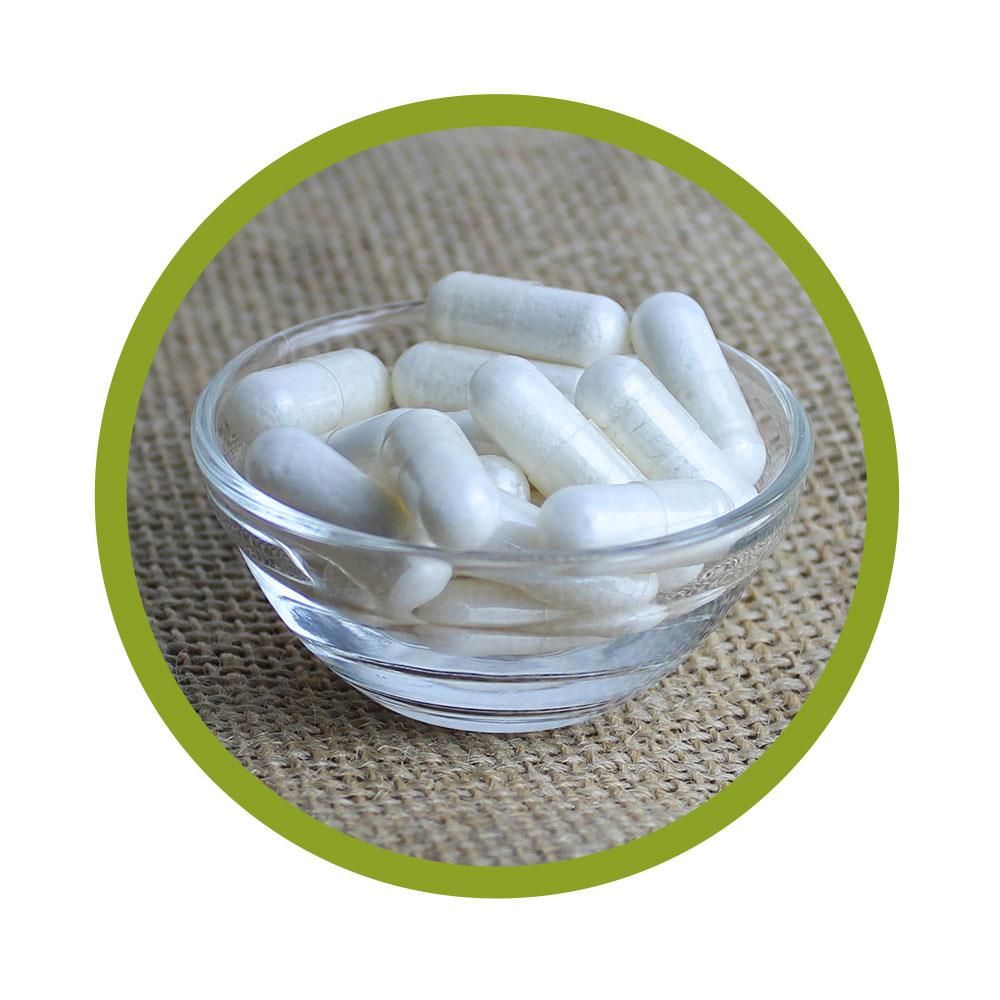 Klare Glasschale mit weißen Kapseln. Auf grobem, beigen Untergrund. Grüne kreisförmige Umrandung.