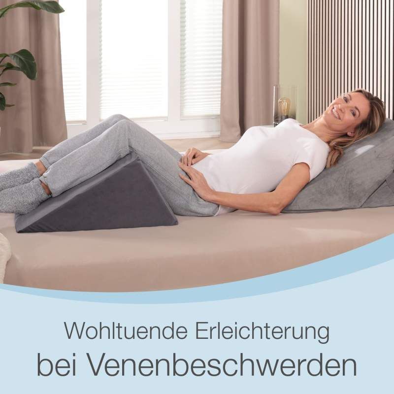 Frau liegt auf Bett mit Keilkissen. Text: Wohltuende Erleichterung bei Venenbeschwerden. Holzlattenwand im Hintergrund.
