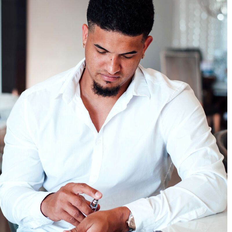 Ein Mann sitzt und sprüht Parfüm auf sein Handgelenk. Aufschrift: EYE OF LOVE Pheromone Parfum Romantic.