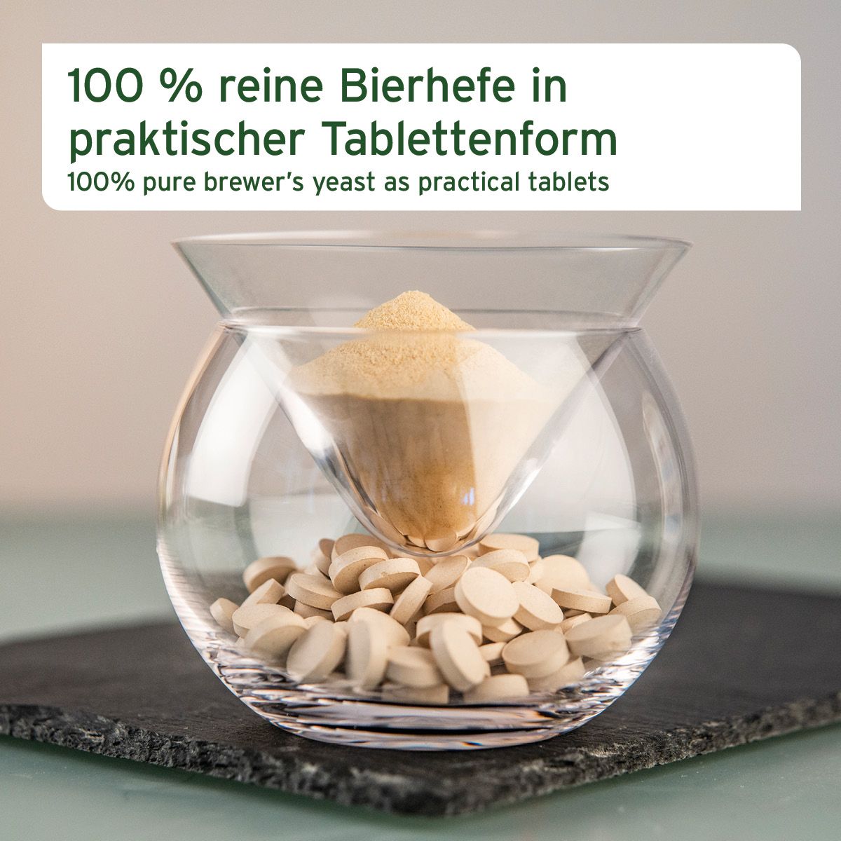 Tabletten und Pulver in einem Glas. Text: 100% reine Bierhefe in praktischer Tablettenform.