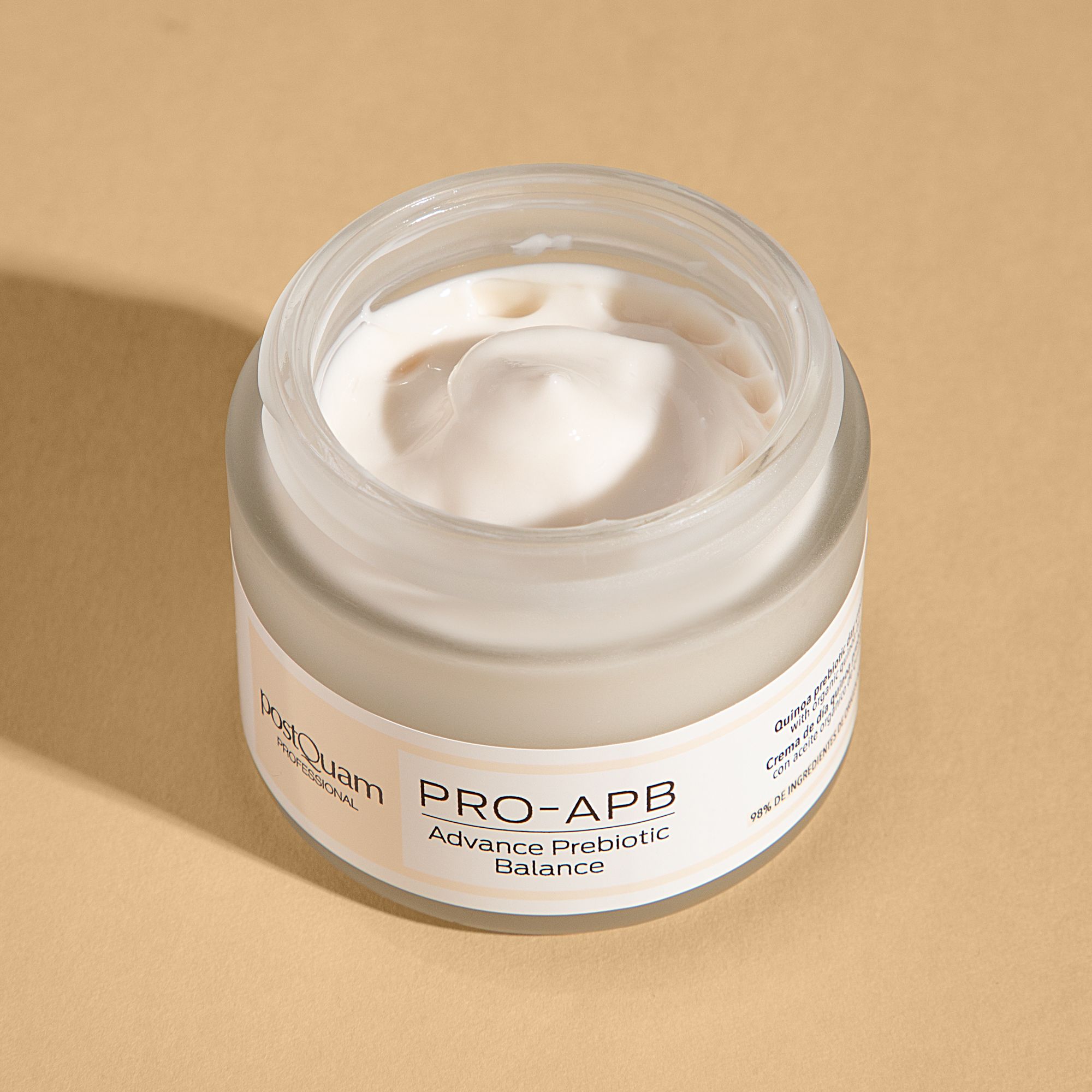 Offenes Creme-Glas. Aufschrift: PRO-APB Advance Prebiotic Balance. Marke: postQuam. Creme sichtbar. Hintergrund: beige.