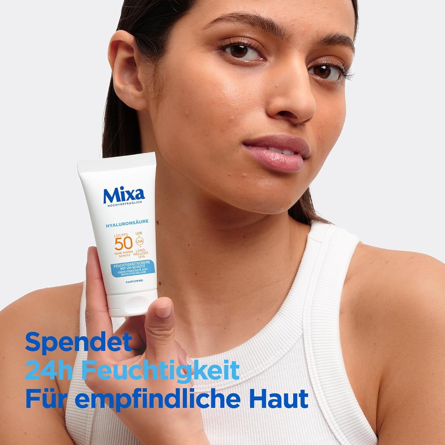 Eine Frau hält eine Tube Mixa UV 50 Hydrating Care. Auf der Tube steht Hyaluronsäure und LSF 50. Die Tube ist weiß mit blauer und oranger Schrift.