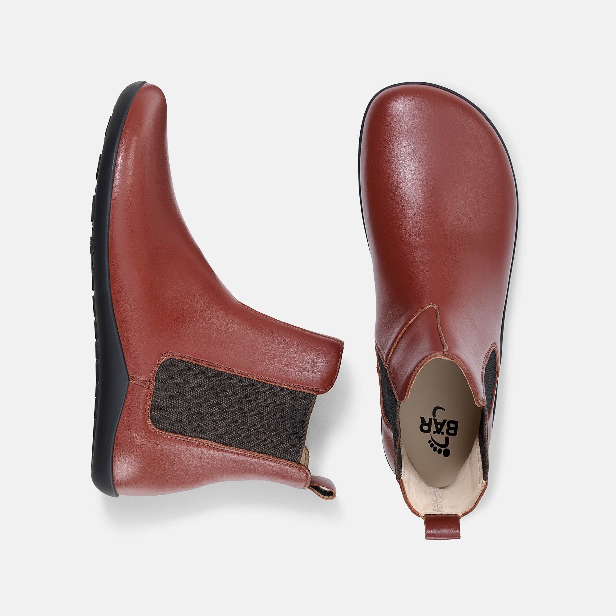 Braune Stiefeletten, seitlicher Gummizug, flache Sohle. Draufsicht auf zwei Schuhe, Sohlen sichtbar.