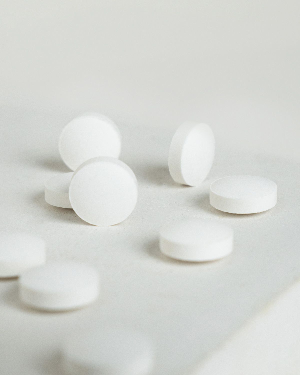 Mehrere weiße Koffein Tabletten auf hellem Untergrund.