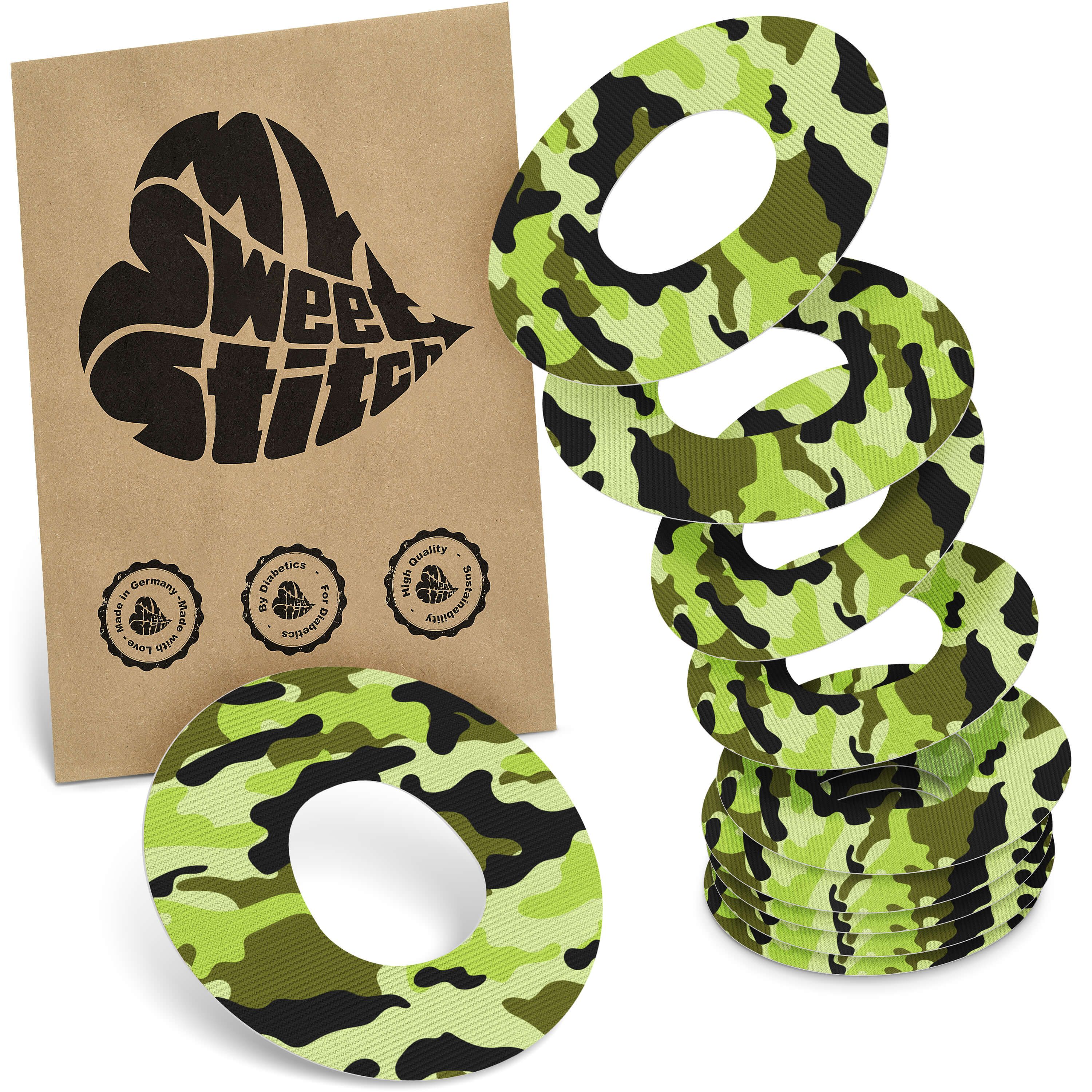 Runde Ringpflaster mit Camouflage-Muster in Grün- und Schwarztönen. Braune Verpackung mit Logo und Siegeln.