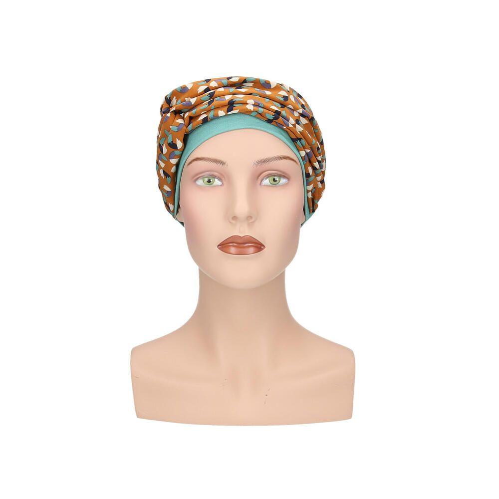 Türkisfarbener Turban mit gemustertem Stirnband auf einer Schaufensterpuppe. Das Stirnband hat ein Muster aus Braun-, Blau- und Beigetönen.