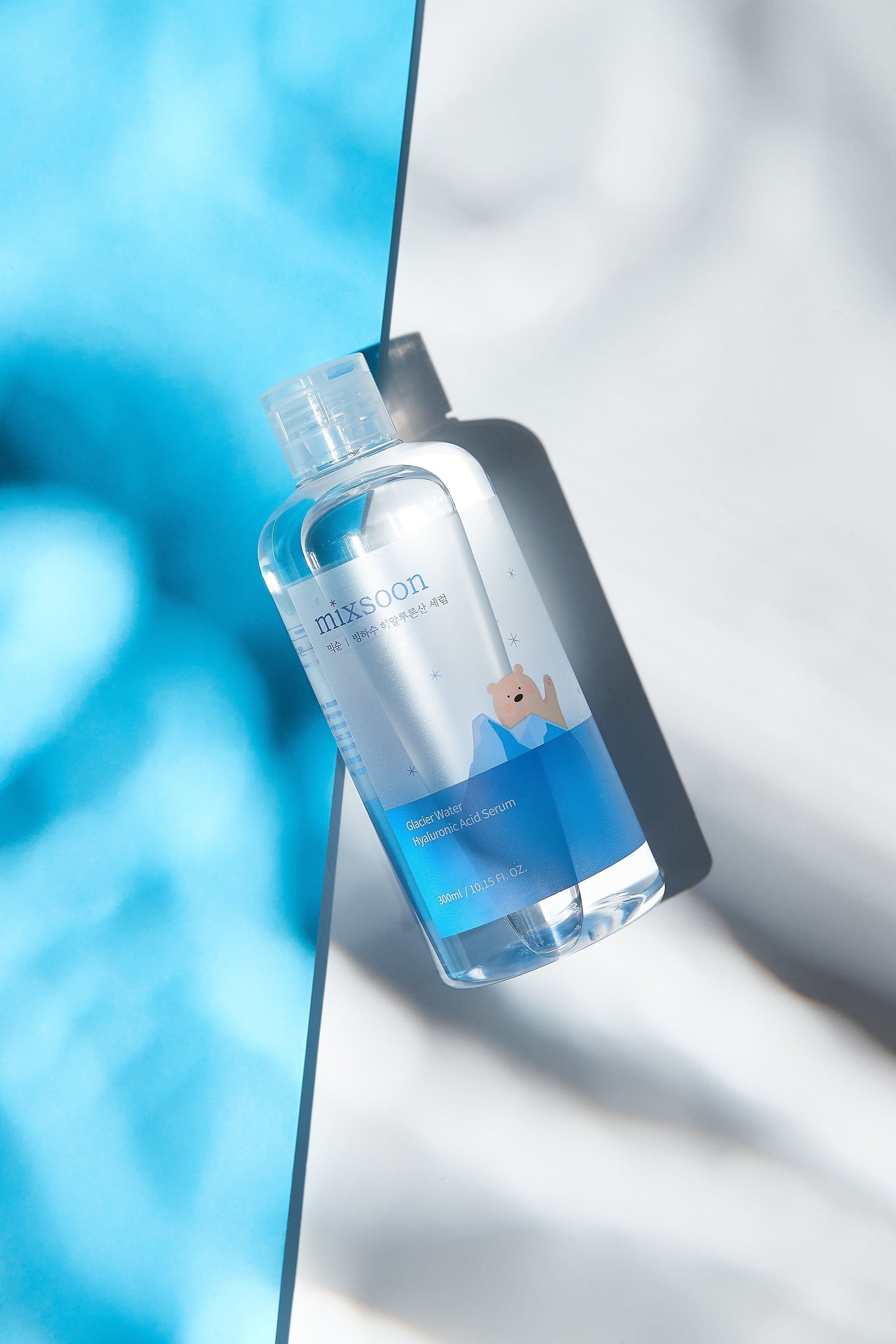 Klare Flasche mit blauem Etikett. Aufschrift: mixsoon Glacier Water Hyaluronic Acid Serum. Produkt auf blauem Hintergrund.