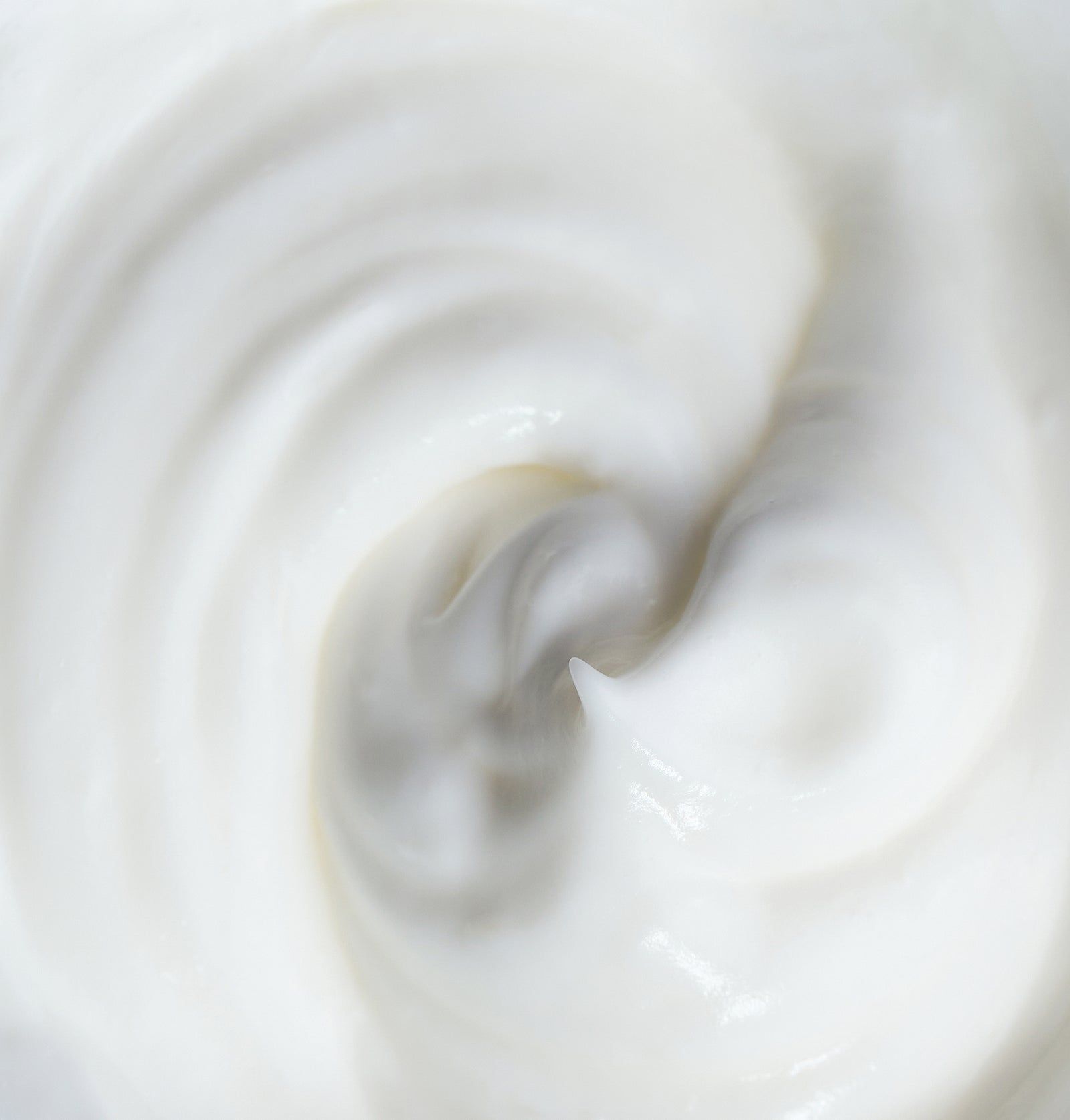 Nahaufnahme von weißer Creme. Cremige Textur, gewirbelt. Keine Verpackung oder Text sichtbar.