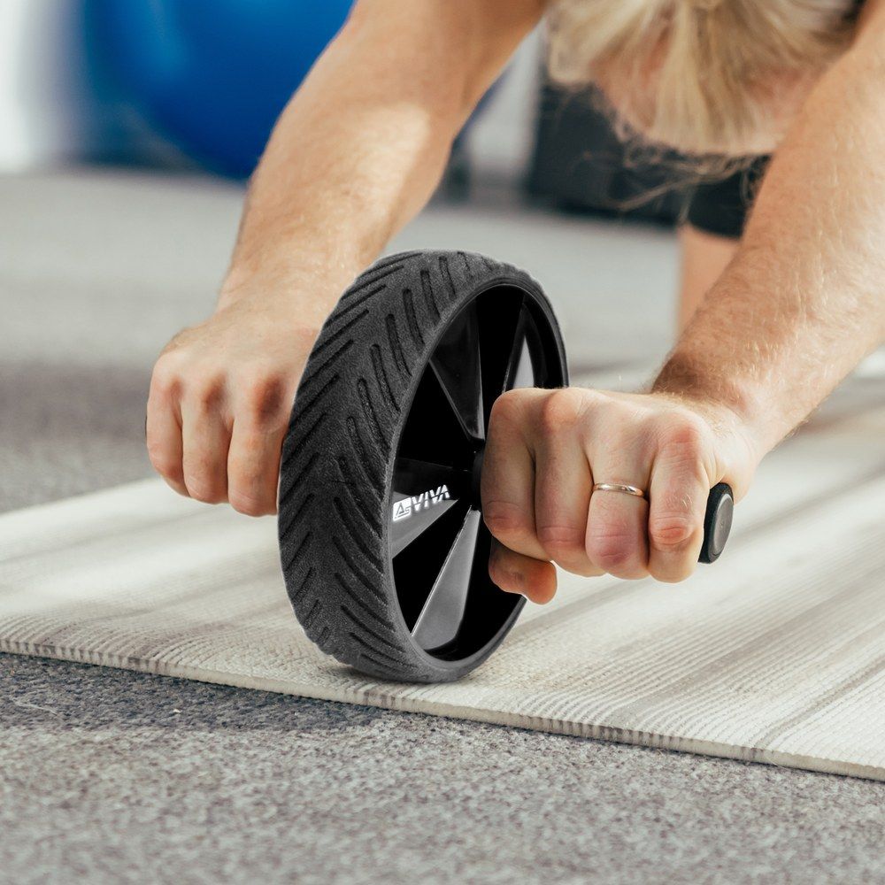 Nahaufnahme von Händen, die einen Bauchtrainer auf einer Matte greifen.